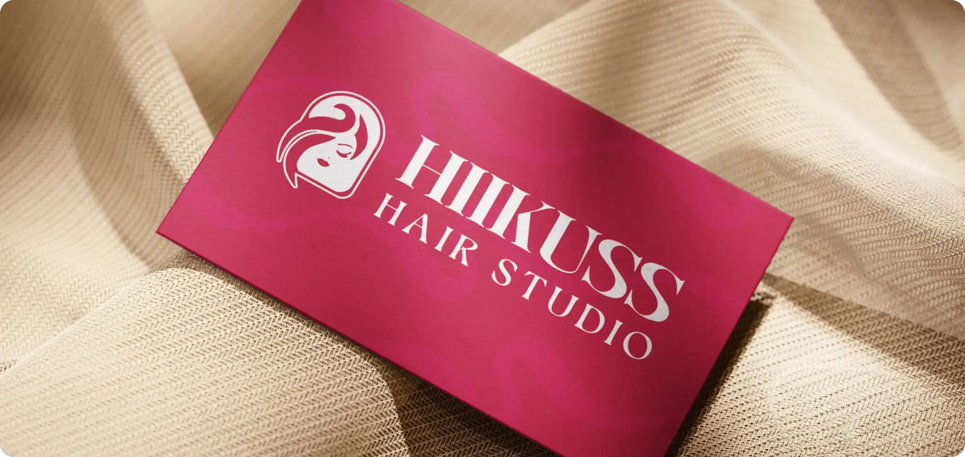 Hiikuss Hair Studio business card in brand red on cream fabric