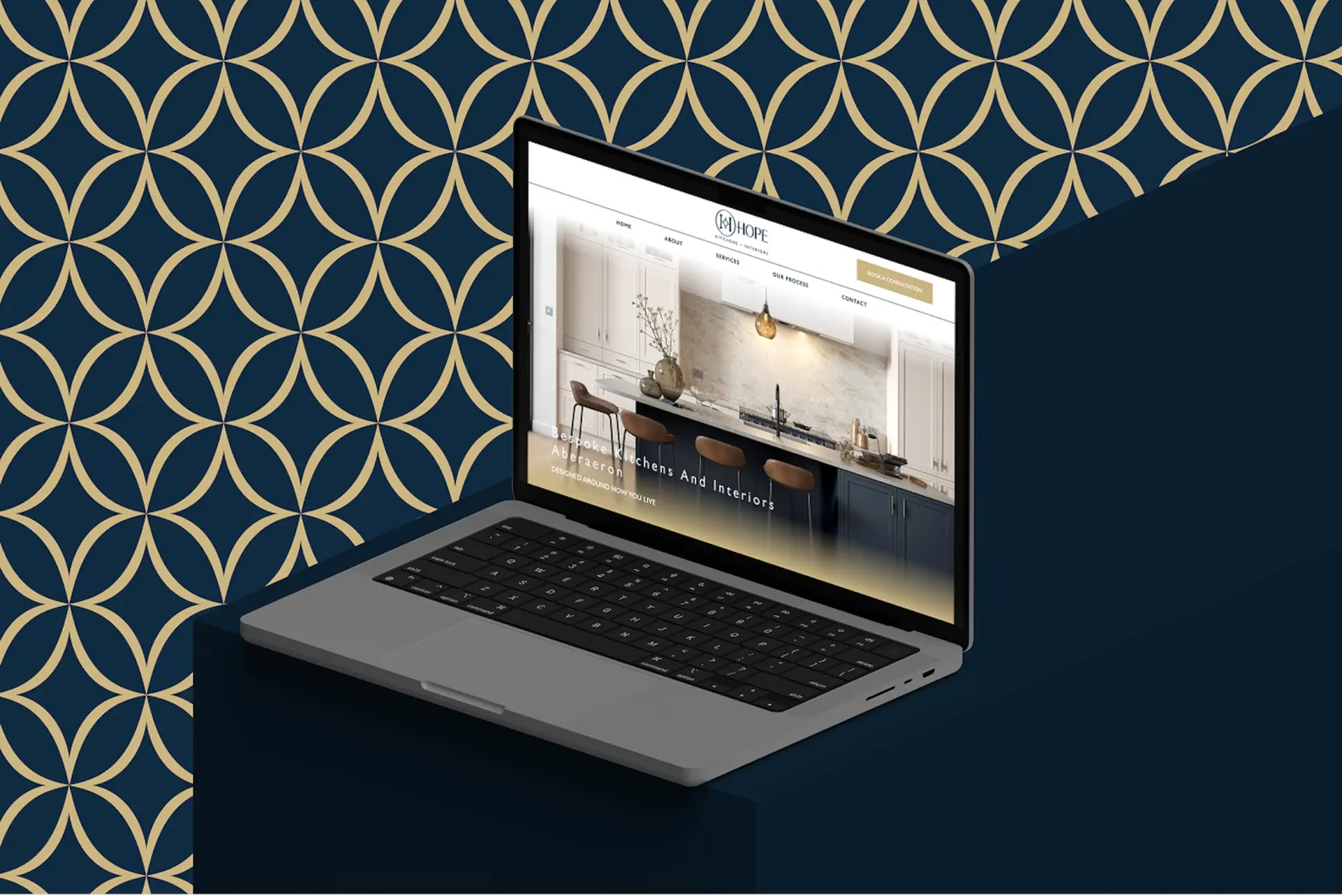 Hope Kitchens home page on a laptop against the brand's gold lattice pattern